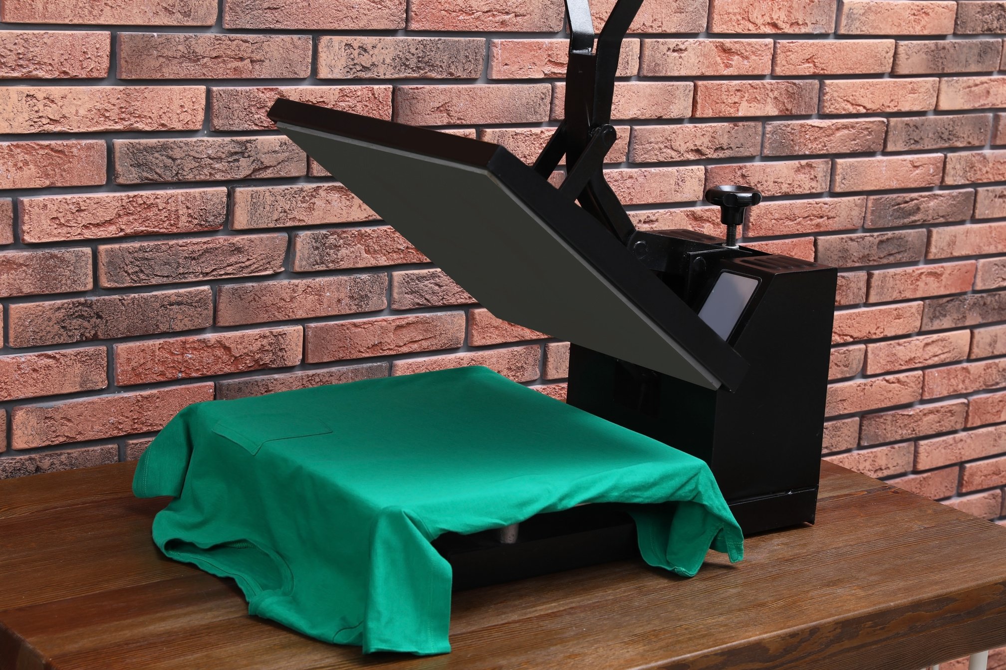 Heat Press Machine with T-Shirt on Wooden Table near Brick Wall